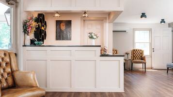 A reception area with a wooden reception desk, a brown leather chair, and a wall-mounted painting.