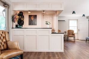 A reception area with a wooden reception desk, a brown leather chair, and a wall-mounted painting.