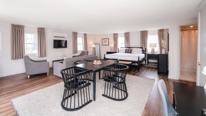 Una habitación de hotel moderna con comedor, sofá, cama y televisor.