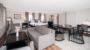Una habitación de hotel moderna con cama, sofá, mesa de comedor y sillas.
