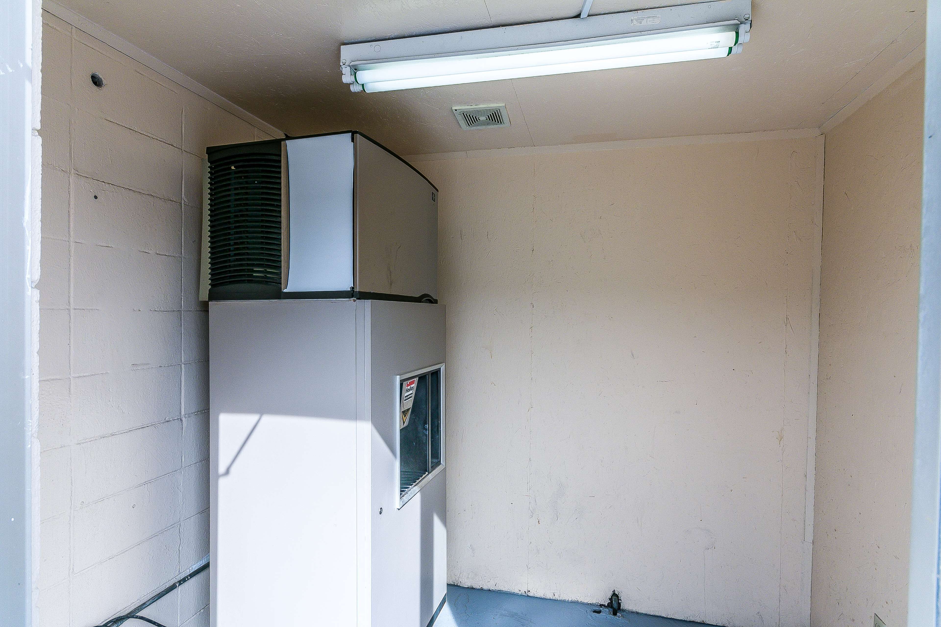 A corner room with a white wall, a window, and a ceiling-mounted air conditioning unit.