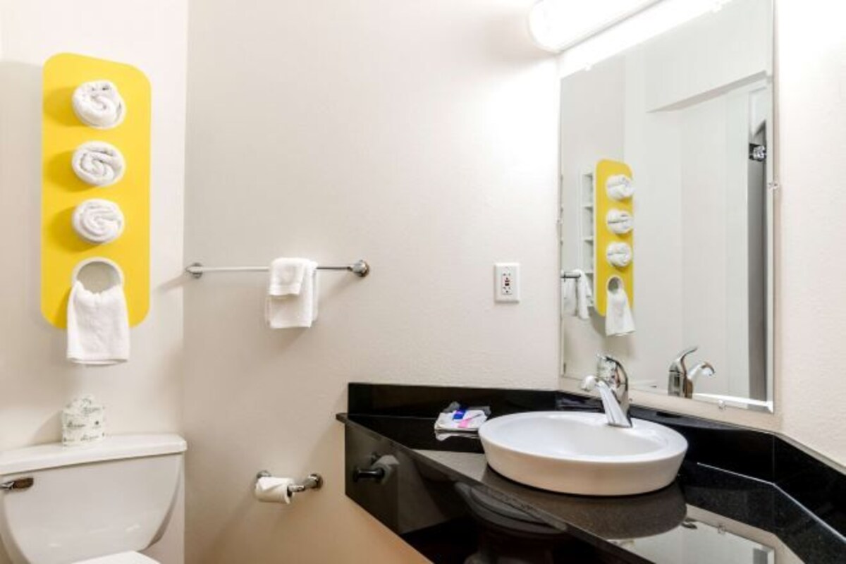 A bathroom with a white sink, a mirror, and a yellow towel rack with towels.