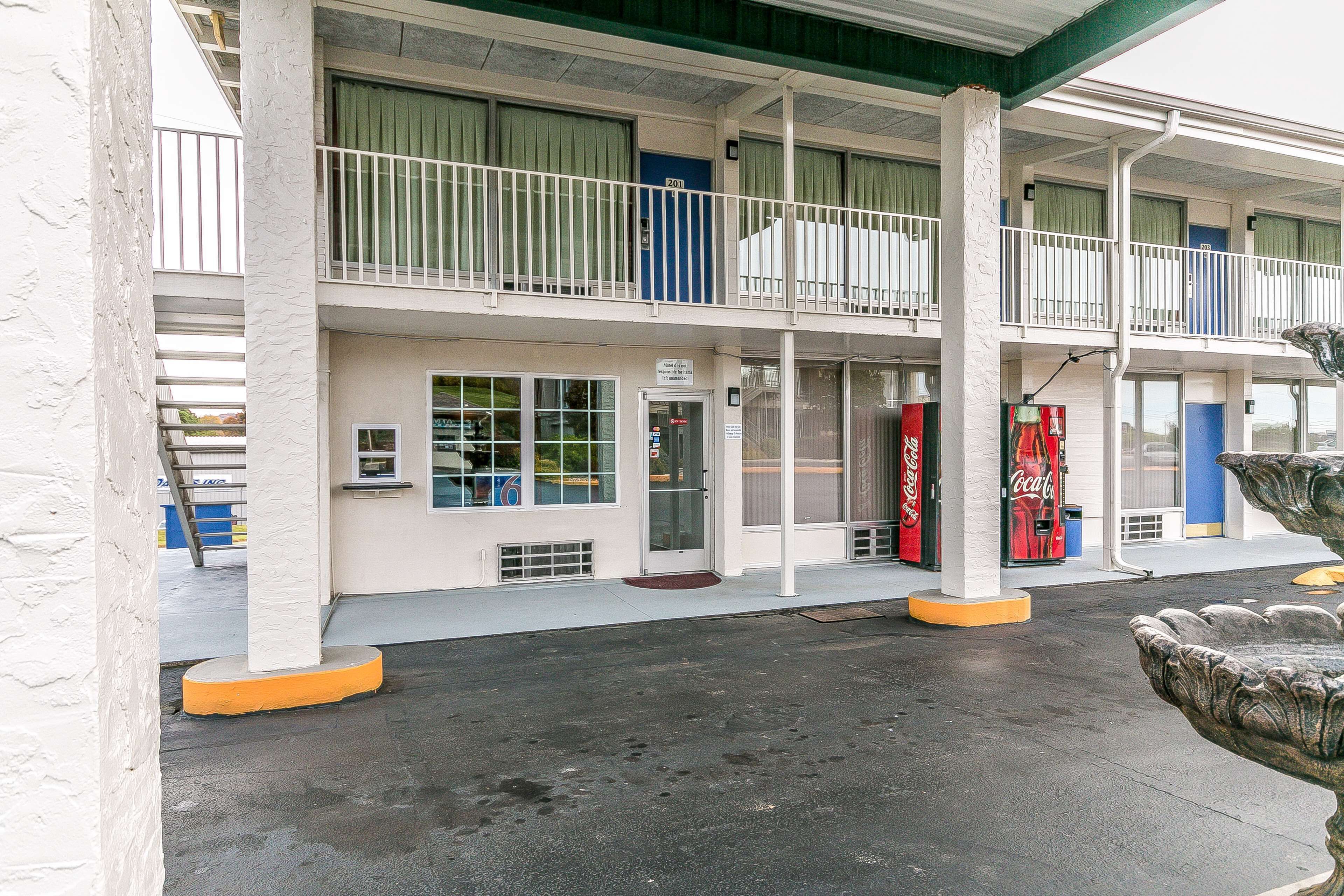 Un motel con una estructura de dos pisos, un porche cubierto y una máquina expendedora de Coca-Cola.