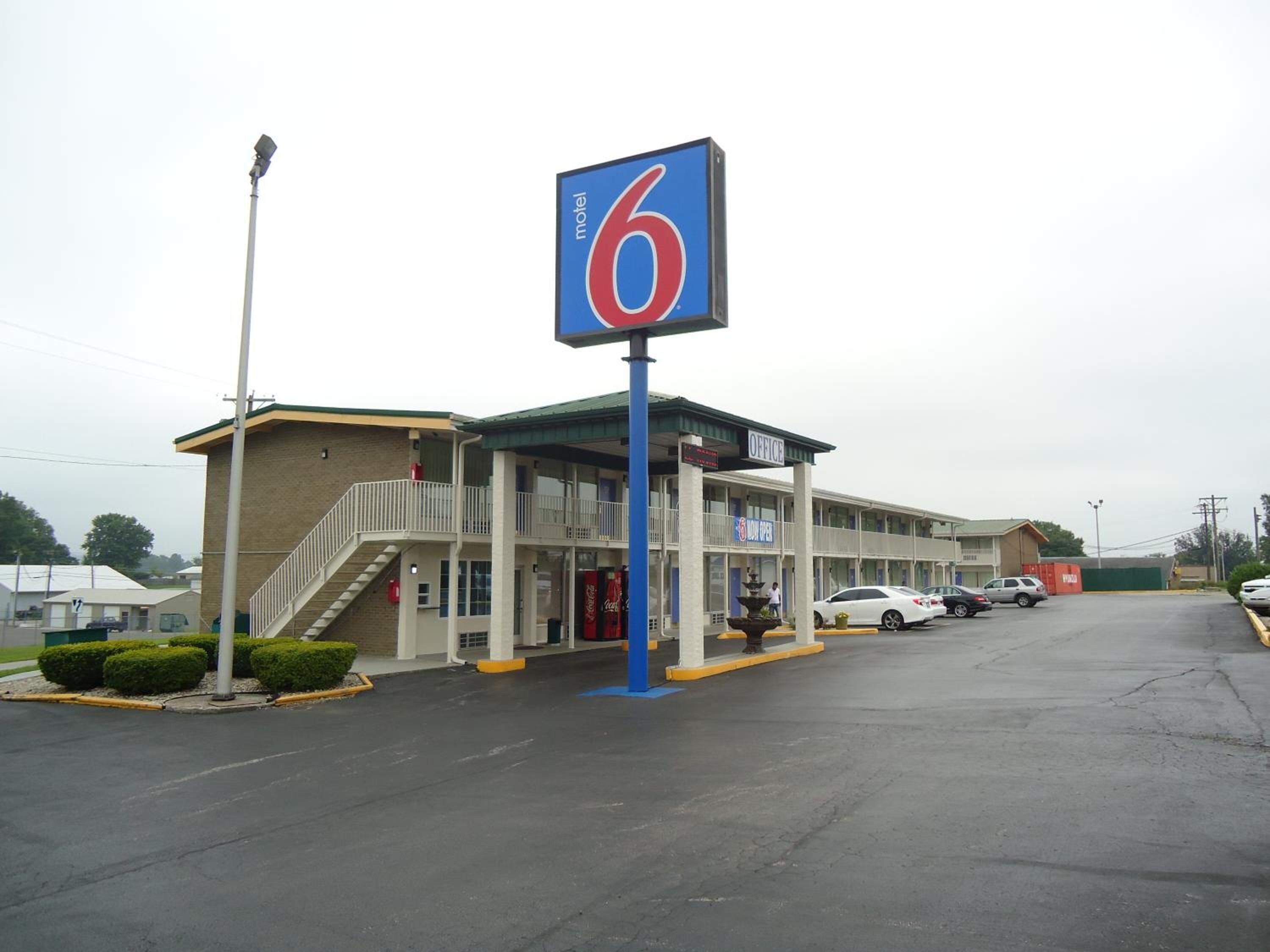 A motel with a prominent '6' sign, a Coca-Cola vending machine, and a visible office area.
