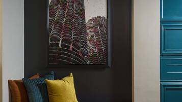 Una habitación moderna con pared oscura, una obra de arte enmarcada, un sofá púrpura con cojines y un mueble azul.