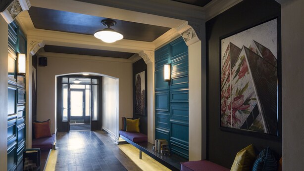 A hallway with a bench, a door, and a wall-mounted light fixture.