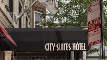 Een hotelentree met een bord waarop 'CITY SUITES HOTEL' staat en een zone voor aanhangwagens.
