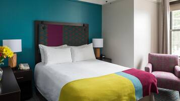 Una habitación de hotel con cama, mesitas de noche, una silla y ventana con cortinas.