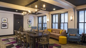 A modern living room with a dining area, large windows, and a unique ceiling light fixture.