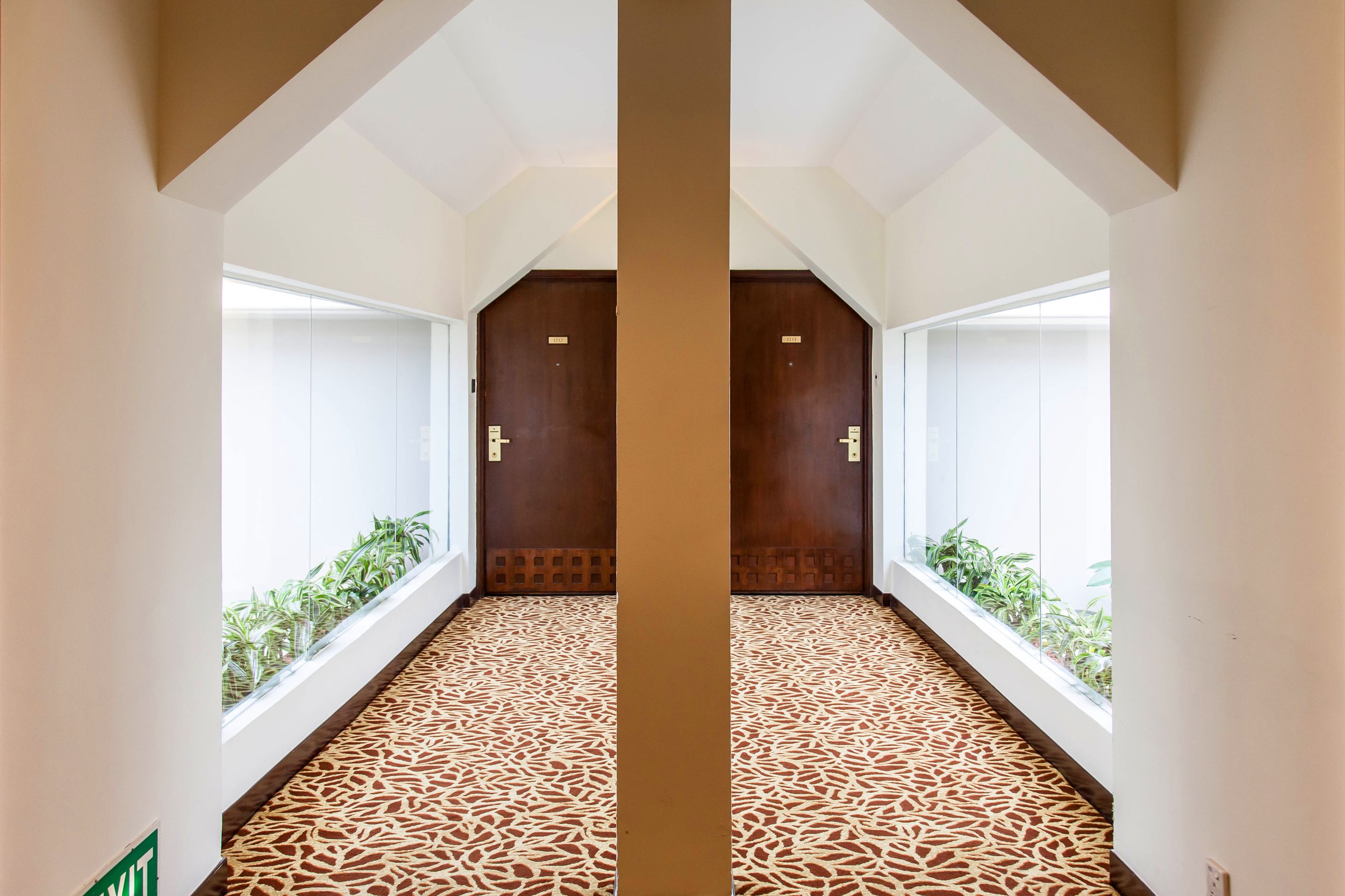 A hallway with patterned flooring, large windows, and wooden doors.