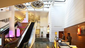 A hotel lobby with an escalator, a reception desk, and a staircase. - Village Hotel Albert Court by Far East Hospitality (Singapore)