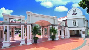 A hotel entrance with a covered walkway, columns, and potted plants. - Village Hotel Albert Court by Far East Hospitality (Singapore)