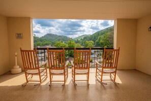 A balcony with three wooden rocking chairs facing a scenic view of a river and hills. - Gatlinburg Chateau Rentals (Gatlinburg)