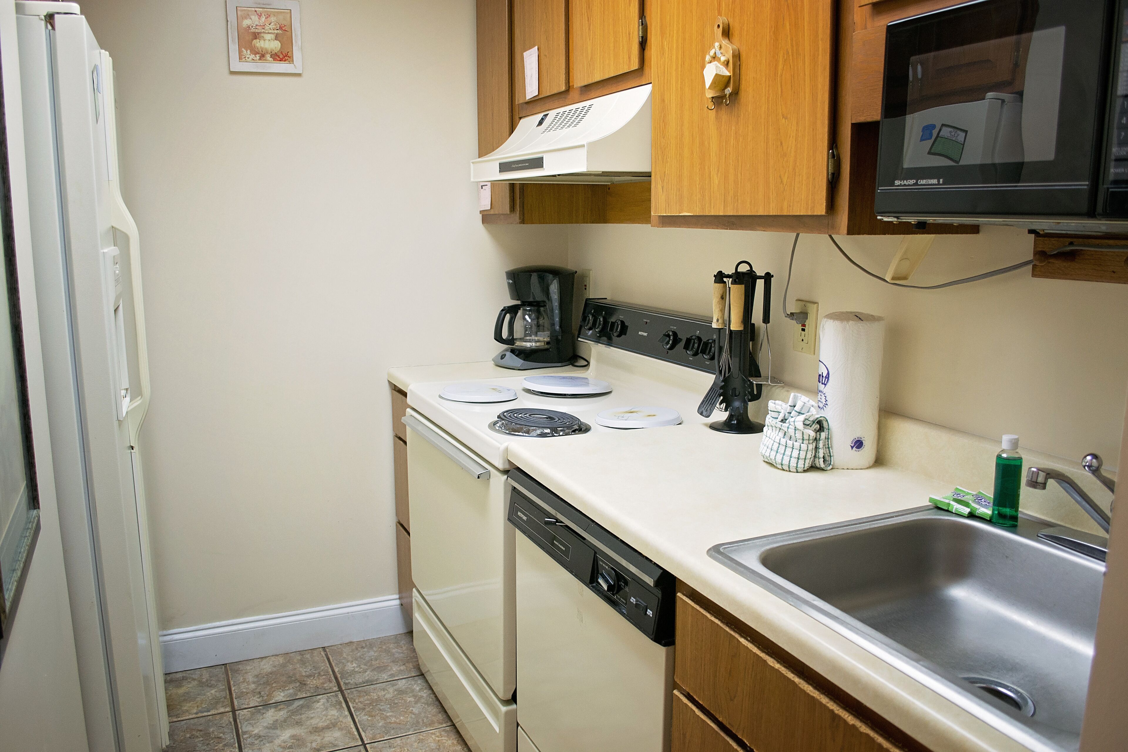 A compact kitchen with a dishwasher, stove, and microwave.
