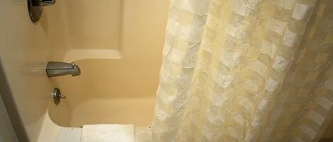A bathroom with a bathtub, a toilet, and a shower curtain.
