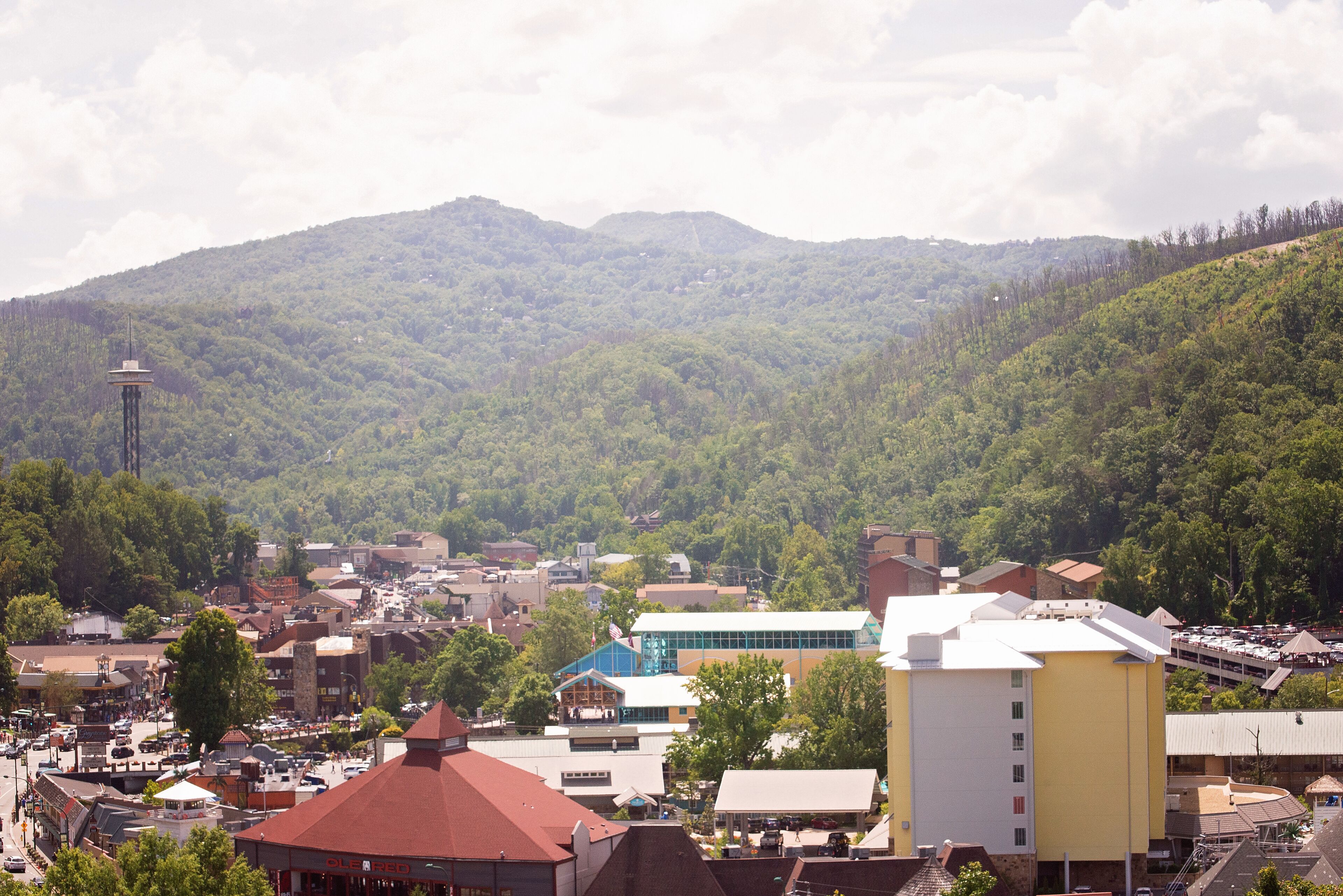 A town with a prominent yellow building, a tower, and a mountainous backdrop.