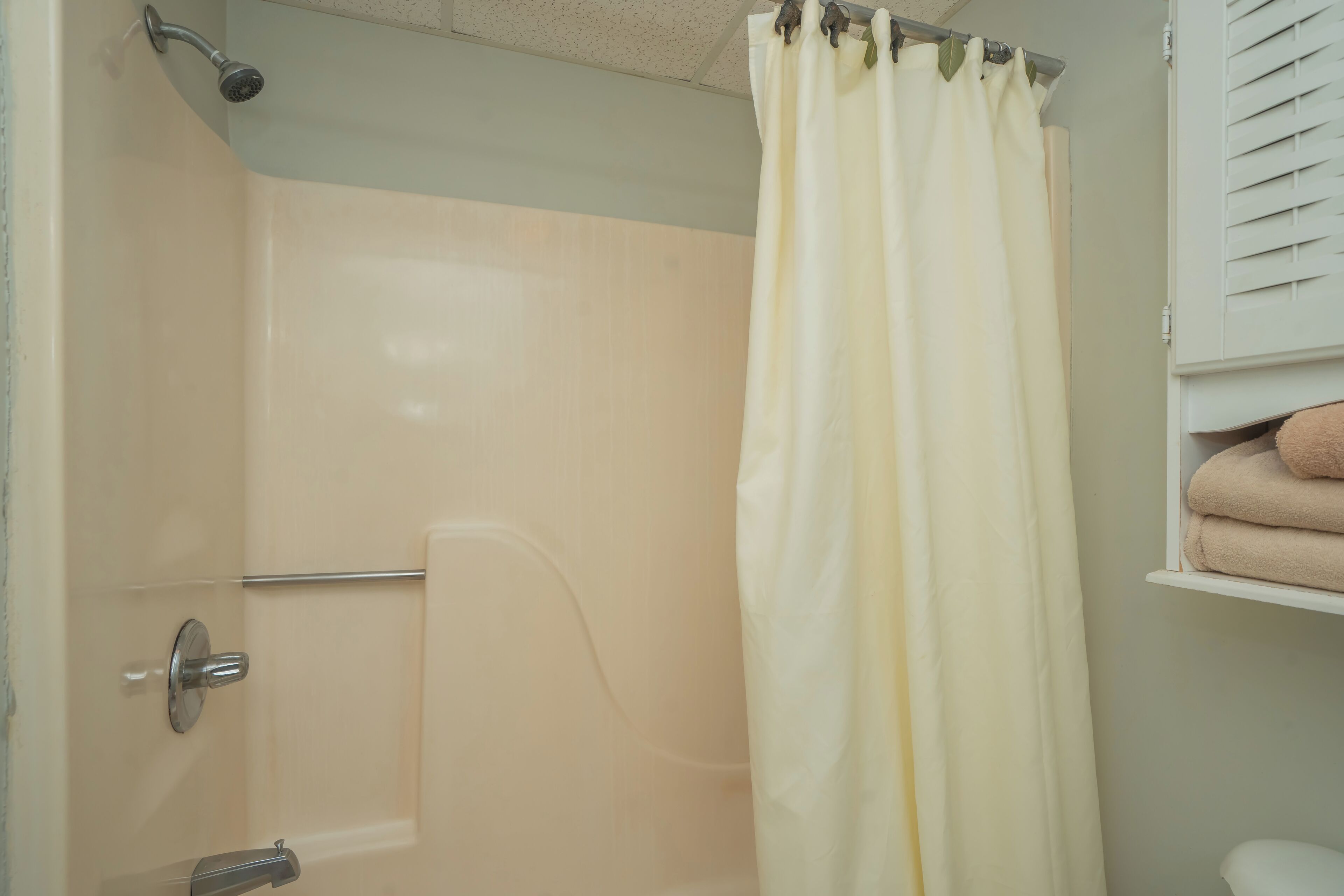 A bathroom with a shower, a toilet, and a towel rack with towels.