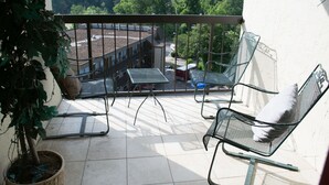 A balcony with metal chairs and a table, overlooking a parking area and greenery. - Gatlinburg Chateau Rentals (Gatlinburg)