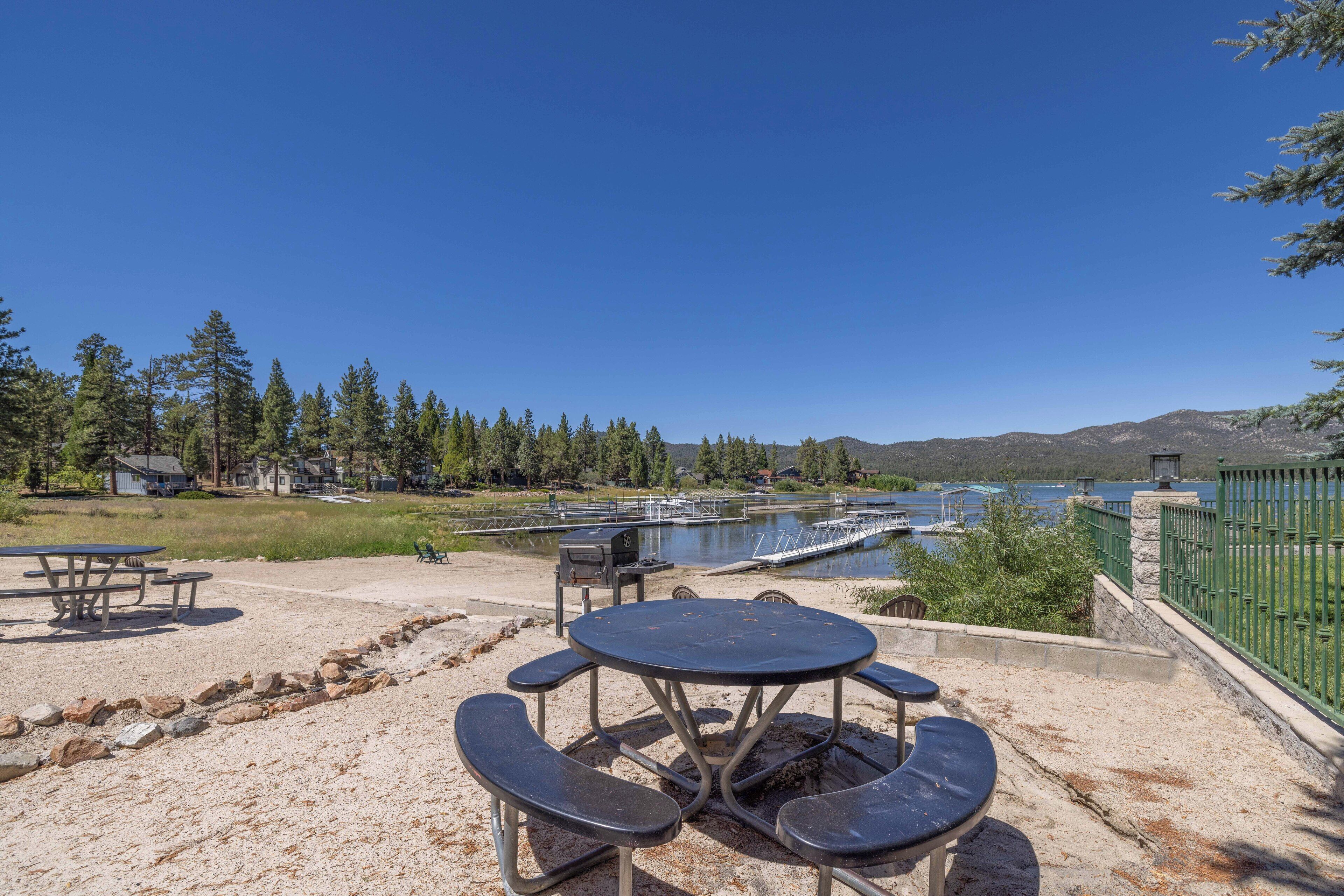 Una mesa de picnic con bancos, vista a un lago y una valla verde.