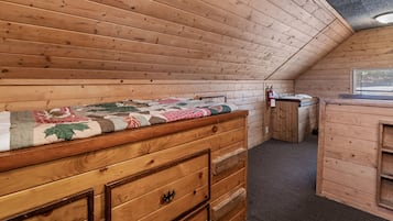 A cozy attic bedroom with a wooden bunk bed, a small desk, and a window.