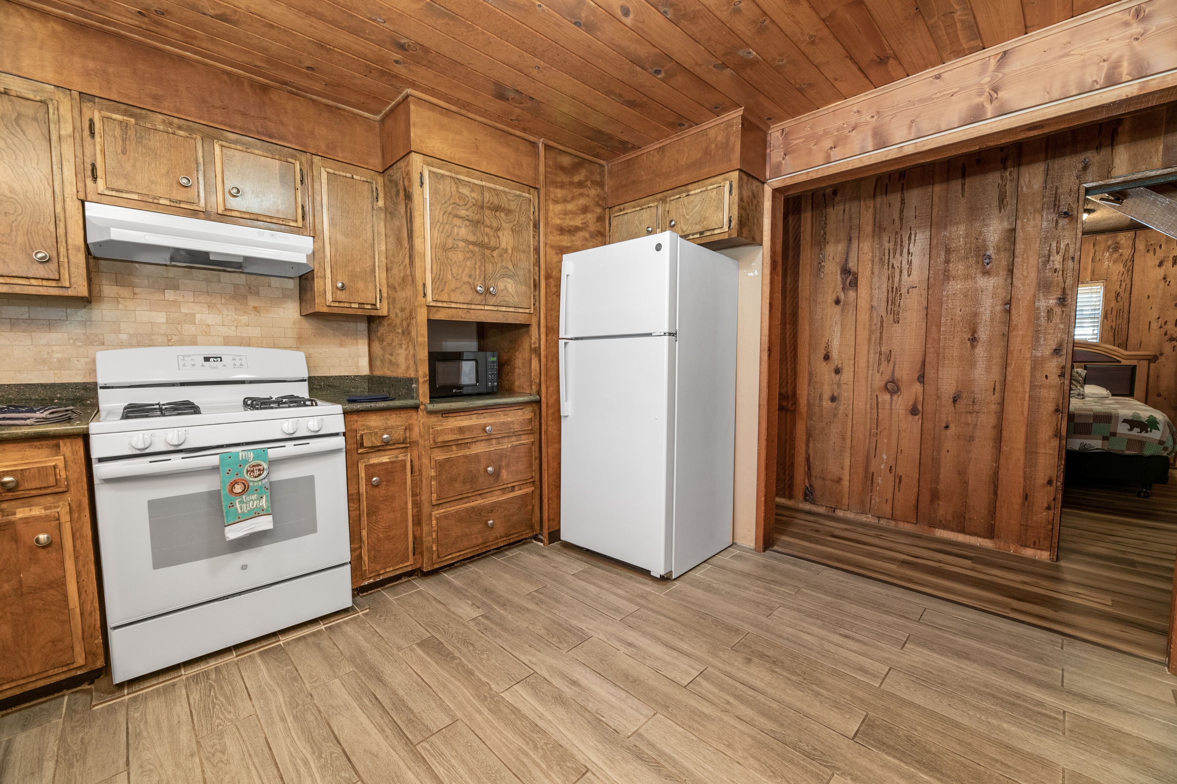 A kitchen with wooden cabinets, a white stove, and a refrigerator.