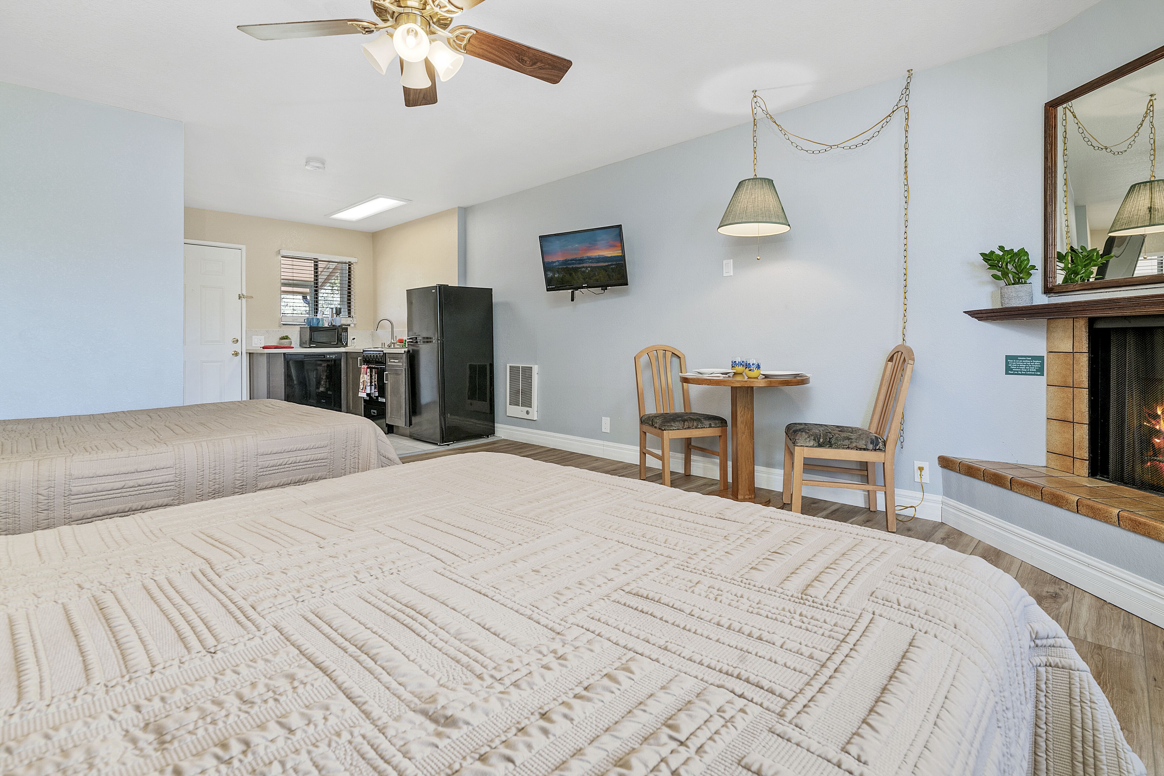 A hotel room with two beds, a television, a fireplace, and a dining area.