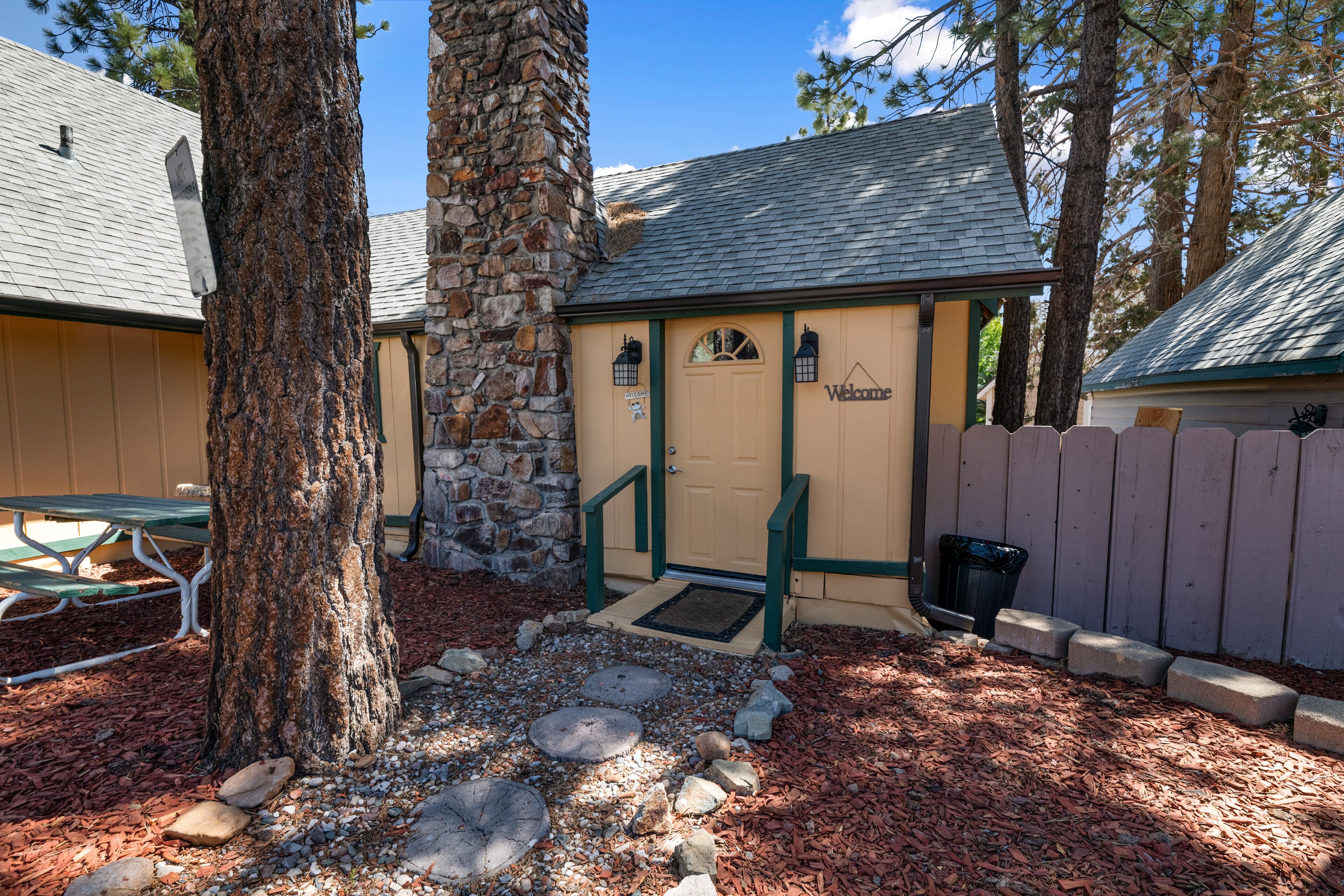 A building with a stone facade, a wooden door, and a 'Welcome' sign.