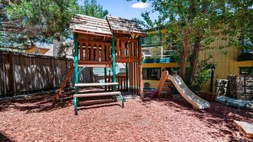 Children can play on the slide and climb in the play area surrounded by a fence.