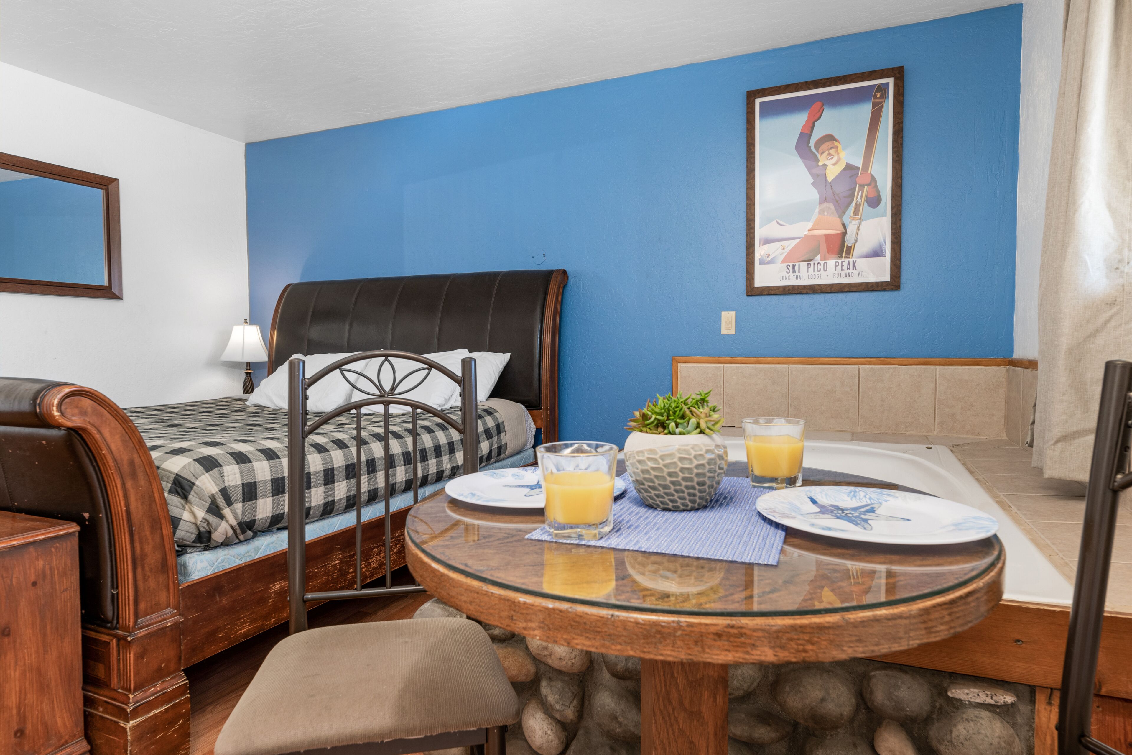 A bedroom with a bed, a dining table with breakfast items, and a poster on the wall.