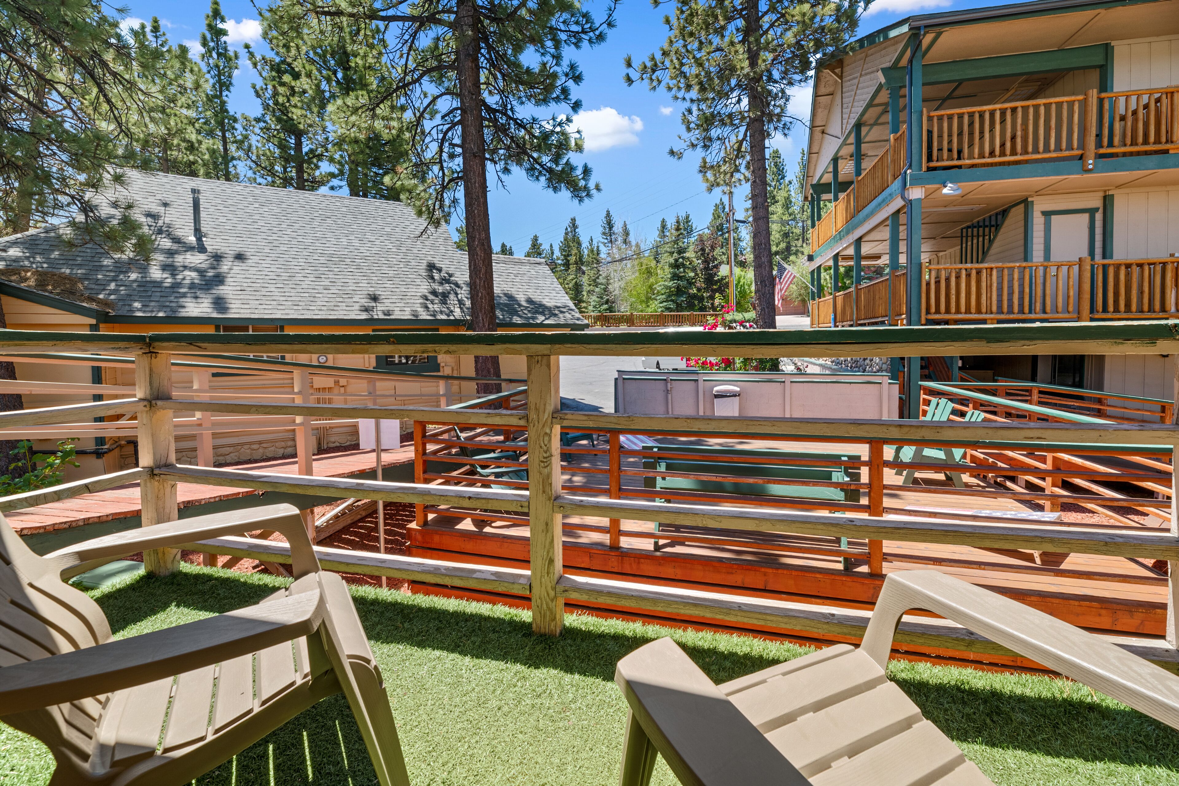 A wooden deck with benches and a view of a building with a balcony.