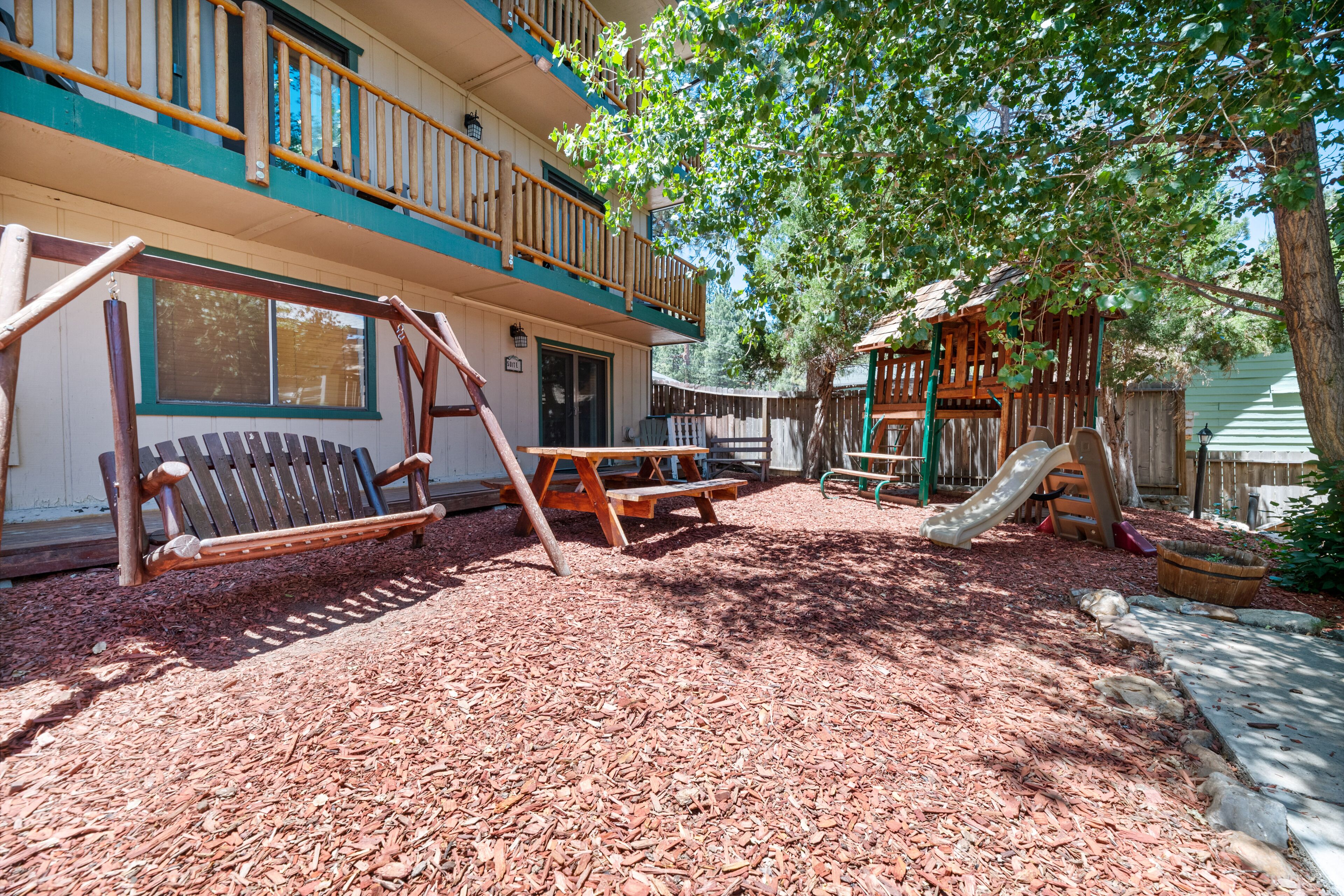 A playground with a swing set, slide, and picnic table.
