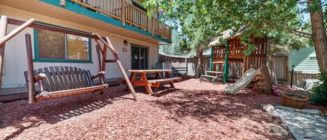 A playground with a swing set, slide, and picnic table.