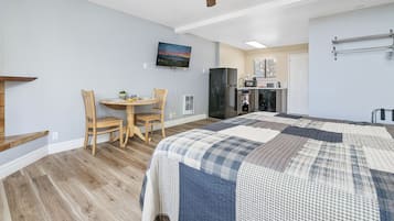 Un dormitorio con una cama grande, una mesa de comedor con sillas, una zona de cocina y un ventilador de techo.