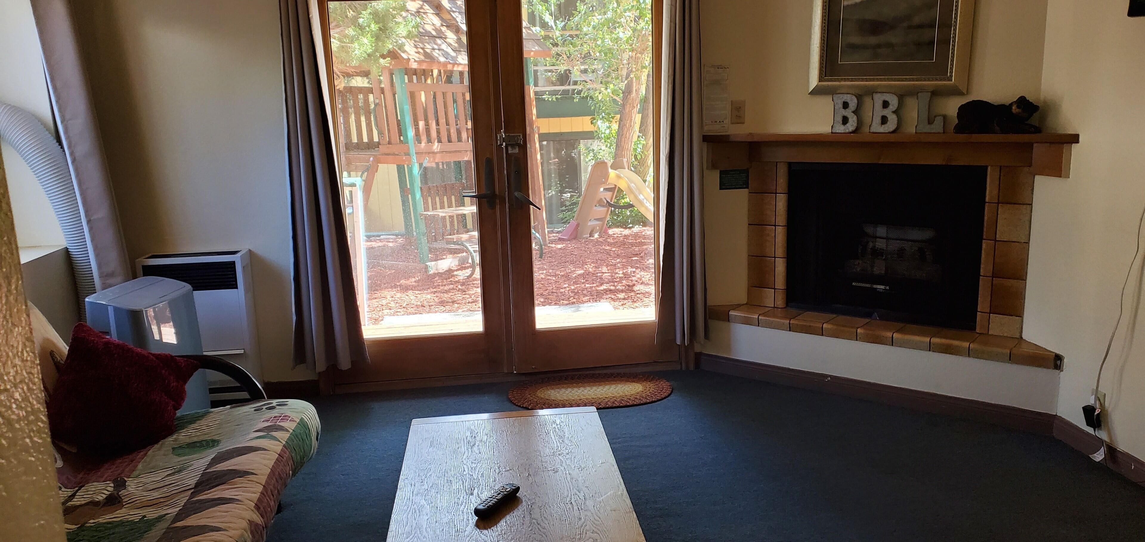 Una sala de estar con un sofá, una chimenea y vistas a una terraza exterior.
