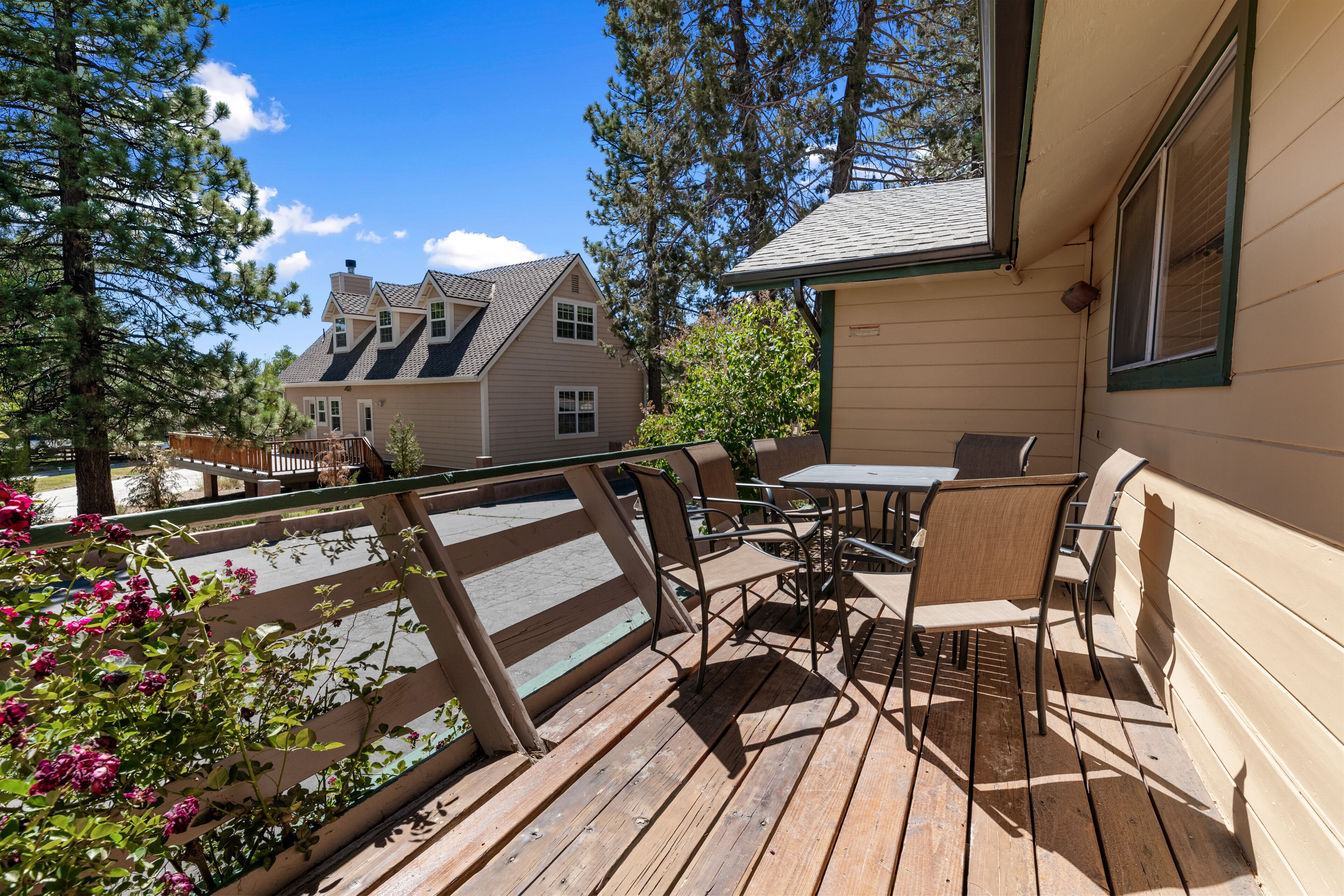 A wooden deck with outdoor furniture, overlooking a residential area with houses and trees.