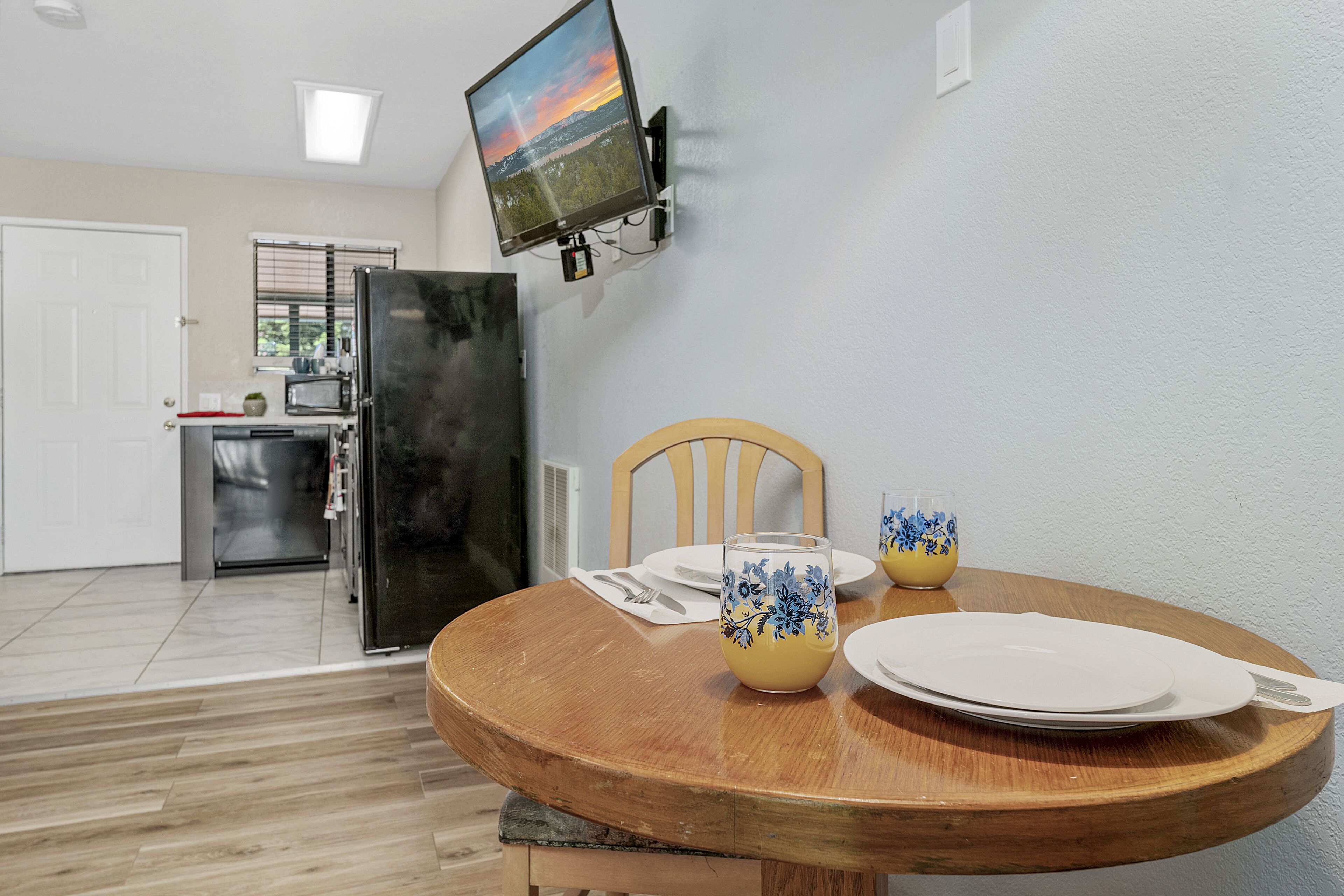 Un coin repas avec une table en bois, deux vases décoratifs et un téléviseur à écran plat fixé au mur.