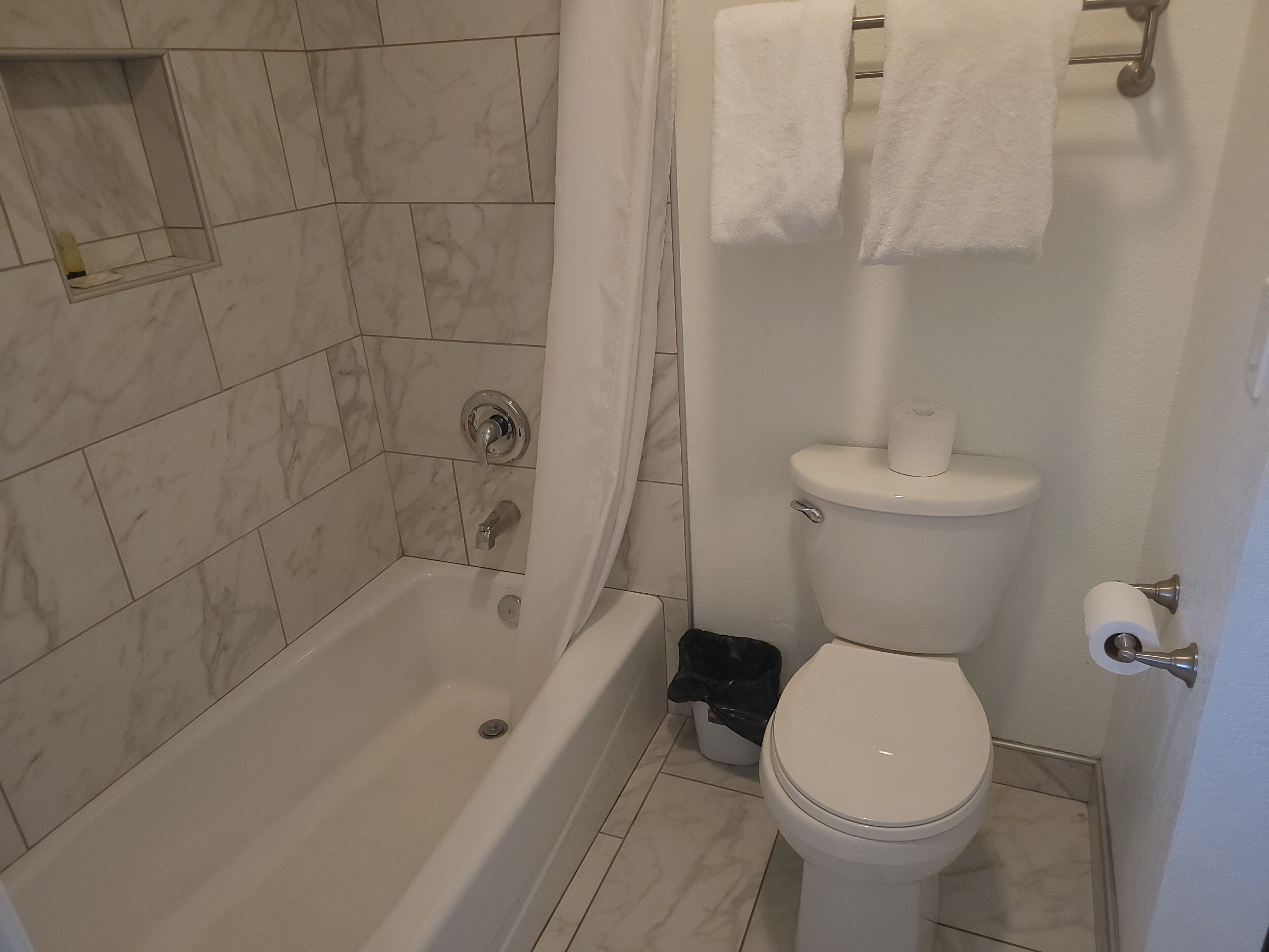 Un baño con bañera, inodoro y cortina de ducha.