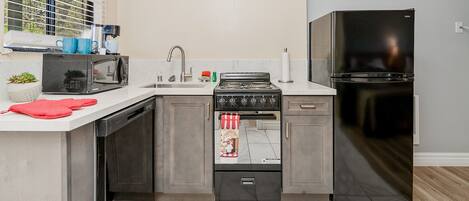 A compact kitchen with a built-in stove, microwave, and refrigerator.