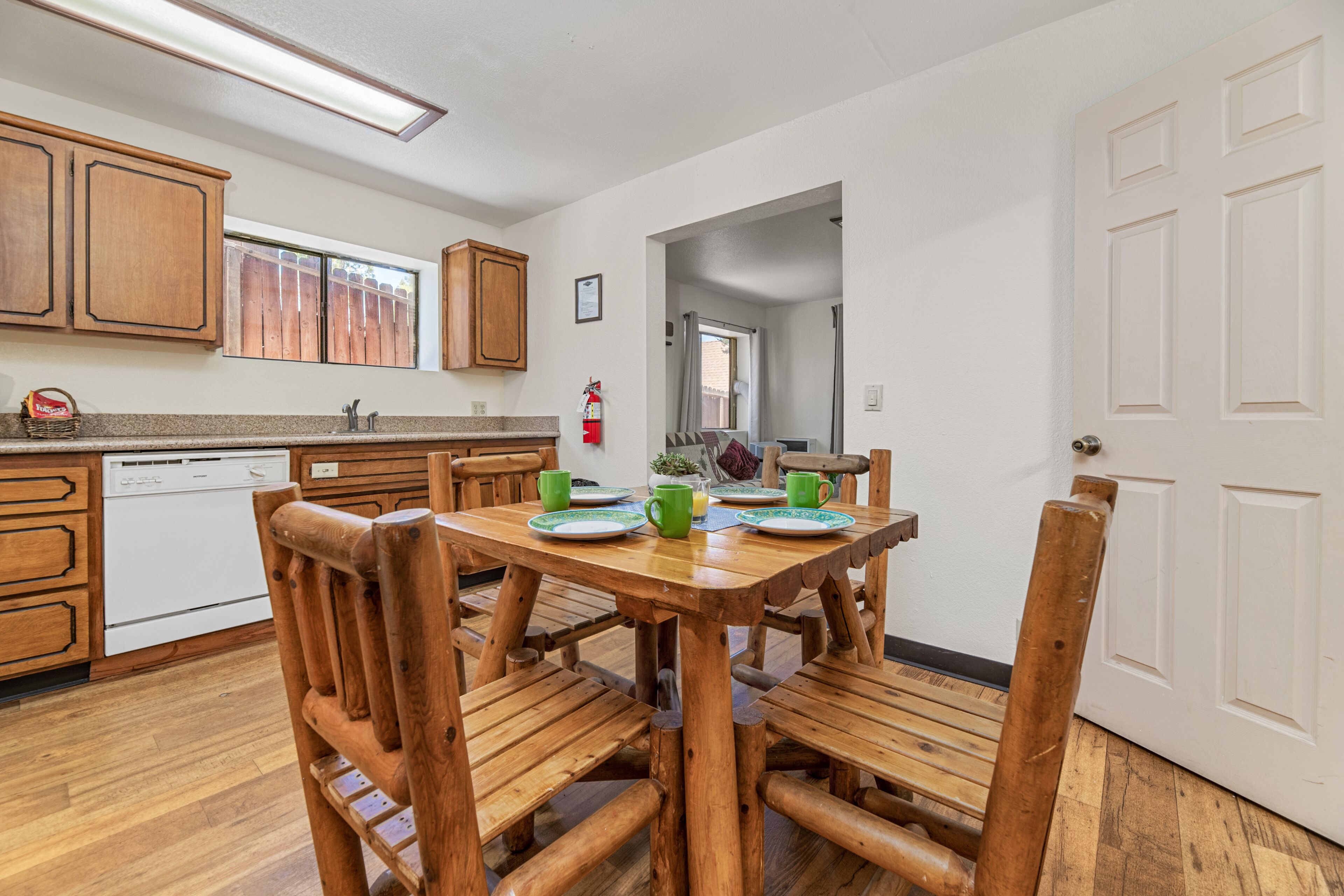A kitchen with wooden cabinets, a dining table with chairs, and a white door.