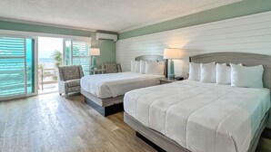 A hotel room with two beds, a chair, and a view of the beach.