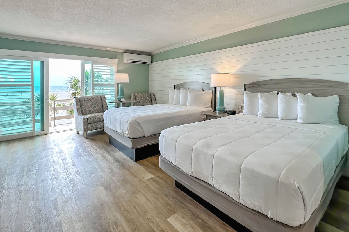 Une chambre d’hôtel avec deux lits, une chaise et vue sur la plage.