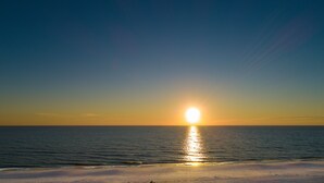 A sunset over a calm sea with a clear horizon.