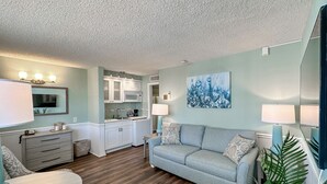 A compact living space with a kitchenette, a dining area, and a seating area with a sofa and lamps.