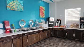 Una cocina con armarios de madera, encimera blanca y diversos electrodomésticos.