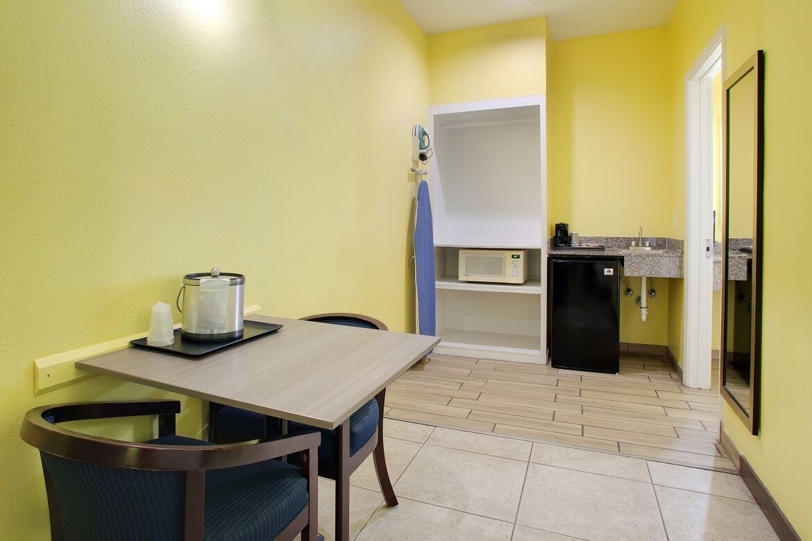A compact kitchen with a dining table, chairs, a microwave, and a coffee maker.