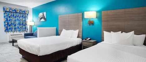 Habitación de hotel con dos camas, una pared azul decorativa, un cuadro y una lámpara.