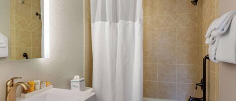 A bathroom with a white sink, gold faucet, and a shower curtain.