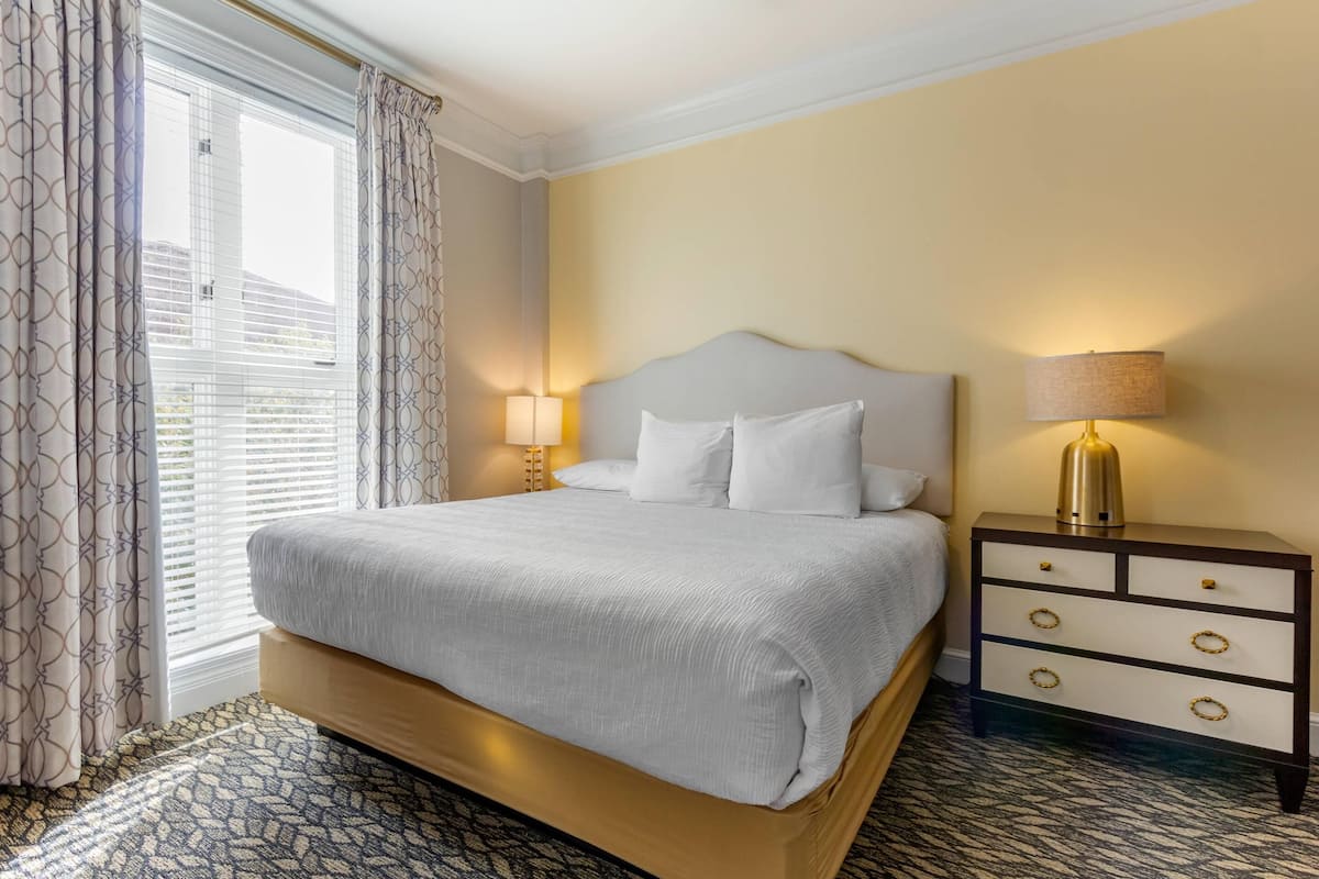 Ein Hotelzimmer mit einem großen Bett, einem Nachttisch mit Lampe und einem gemusterten Boden.