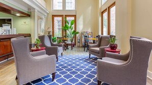 A spacious lobby with a blue patterned carpet, comfortable seating, a reception desk, and large windows allowing natural light. - Church Street Inn Historic Charleston, Ascend Collection Hotel (Charleston)