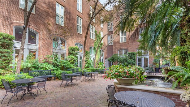 A courtyard with brick buildings, outdoor tables and chairs, a small water feature, and lush greenery. - Church Street Inn Historic Charleston, Ascend Collection Hotel (Charleston)